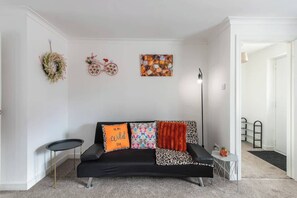 A living room with a black sofa, a small round table, and a floor lamp.