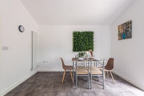 A dining area with a table, chairs, a wall-mounted plant, and a clock on the wall. - Beverley Central Quiet 3 bedroom Homey Parking (East Riding of Yorkshire)