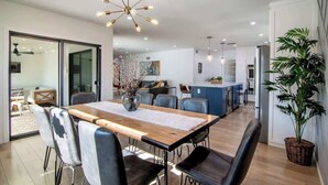 A modern kitchen with a central island, a dining area with a wooden table and chairs, and a large potted plant. - Private Pool · Remodeled Los Angeles Home (Los Angeles)