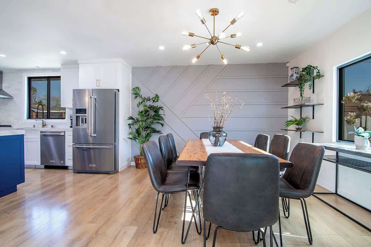 Una cocina moderna con comedor, que incluye una mesa de madera, sillas negras y un refrigerador de acero inoxidable.