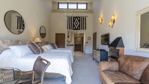 A hotel room with two beds, a sofa, a chair, a fireplace, and a large mirror. - Valley Vista Escape (Durango)