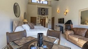 A spacious bedroom with a large bed, a sitting area with a glass table, and a fireplace. - Valley Vista Escape (Durango)