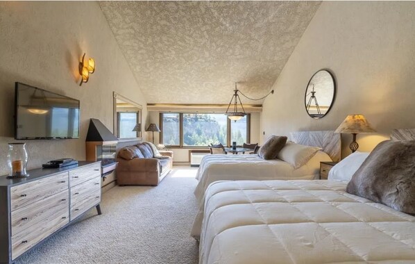 A bedroom with two beds, a desk, a dresser, and a large window offering a view of the outdoors. - Valley Vista Escape (Durango)