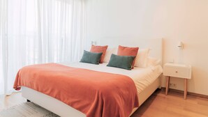 A bedroom with a bed, white curtains, a nightstand, and a lamp. - Oporto Yellow Apartments104 (Porto)