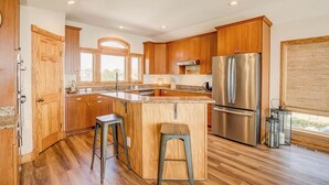 Une cuisine moderne avec des meubles en bois, des appareils en acier inoxydable et un grand îlot central doté de tabourets.
