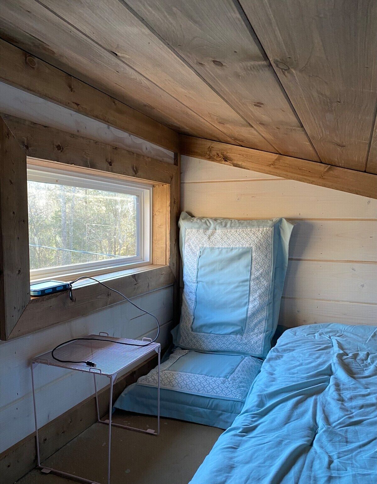 Une petite pièce de cabine avec une fenêtre, un lit et un bureau équipé d’un ordinateur.