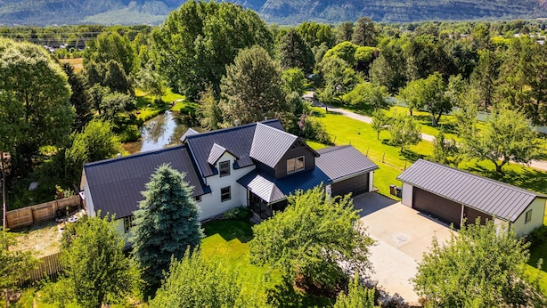 Una casa con un patio amplio, un estanque y montañas al fondo.