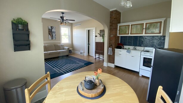 A spacious living room with a large window, a dining area with a wooden table, and a kitchen with white cabinets and a black refrigerator. - Cozy 1-bedroom apartment in lovely Alma with WiFi, AC (Alma)