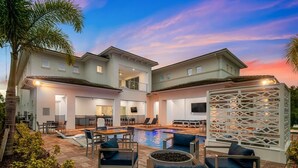 A two-story building with a swimming pool, outdoor seating, and a covered patio area. - Fairway Tropic Oasis: Themed Bedrooms, Arcade, Basketball Court, Near Disney (Kissimmee)