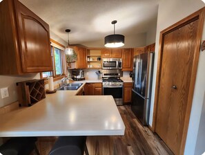 A kitchen with wooden cabinets, stainless steel appliances, a central island, and a pendant light.
