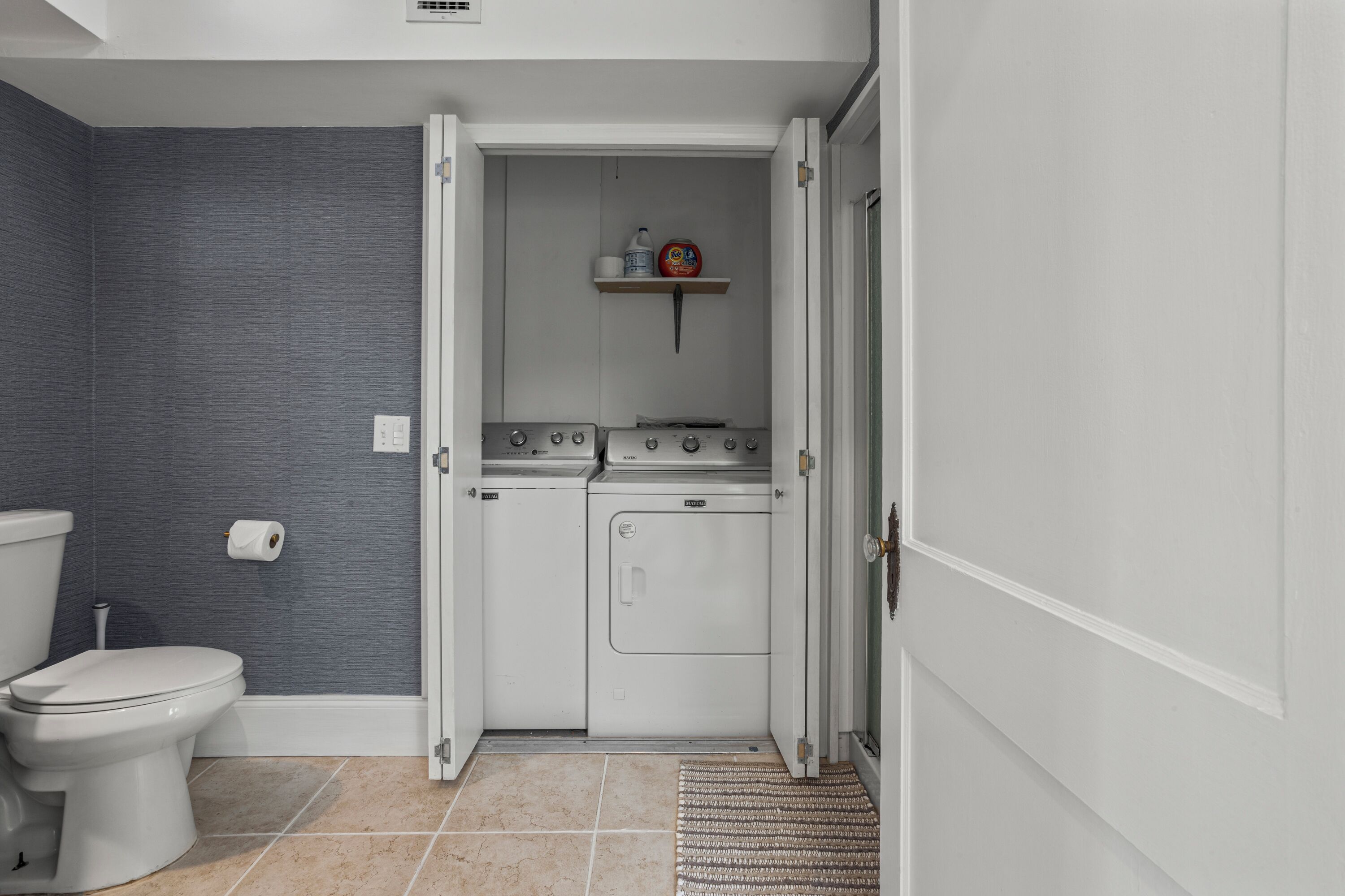 Un baño pequeño con inodoro, lavadora y secadora.
