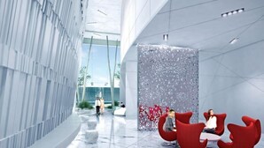 A modern lobby with a curved wall, red seating, and marble flooring. - Lovely Downtown Condo with Iconic CN Tower View! (Toronto)
