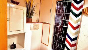 A compact bathroom with a toilet, a sink, and a shower area.
