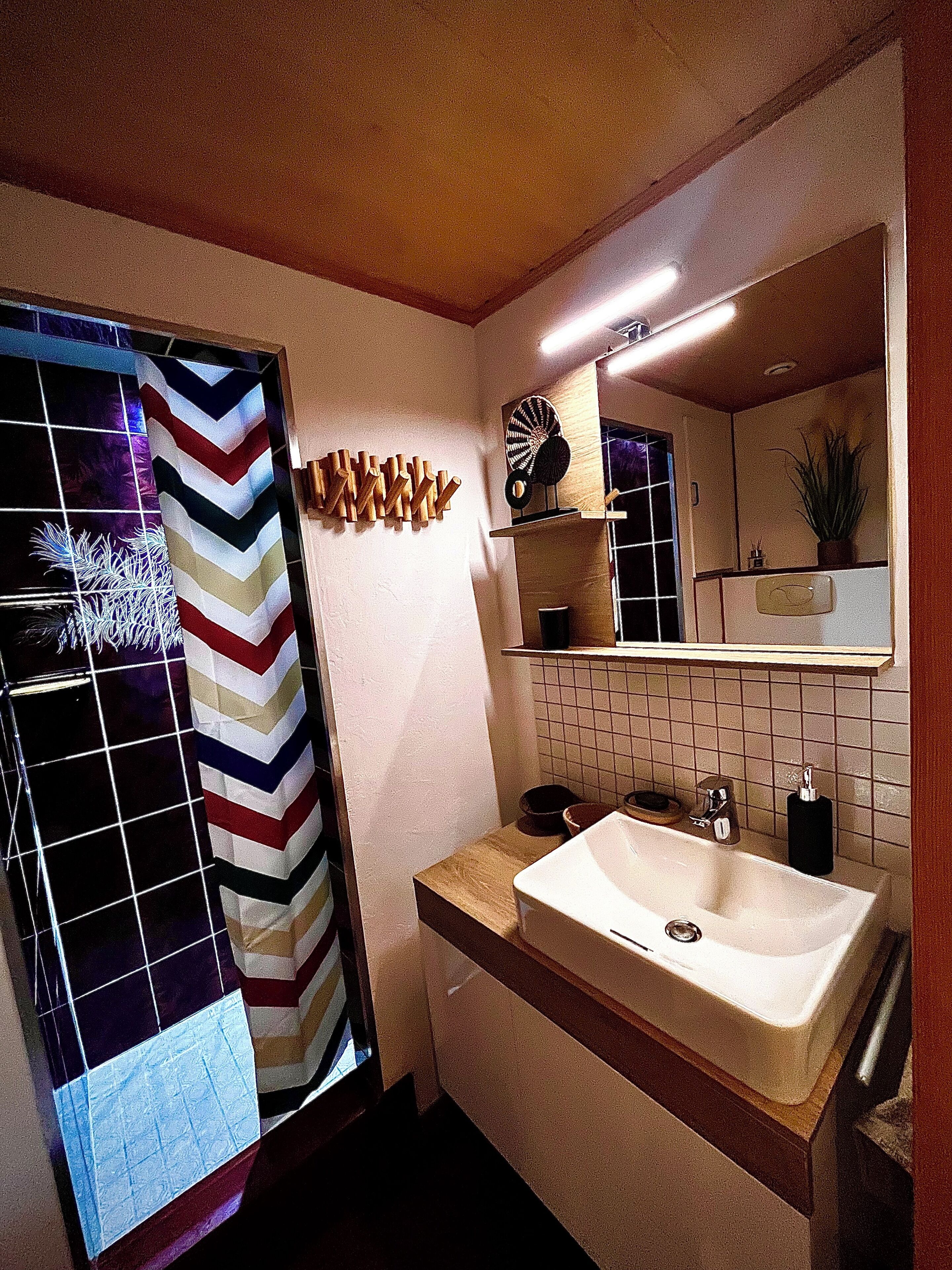Un baño con un espejo grande, un lavamanos y una zona de ducha.