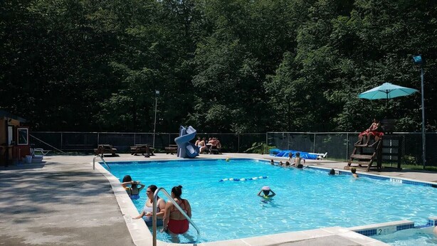 A swimming pool with a diving board and lounge chairs.