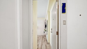 A hallway with a wooden floor, white walls, and a door marked with the number 2. - Leisure Loft Refreshed By the Ocean (San Juan)