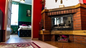 A room with a brick fireplace, a bed with a green headboard, and a red accent wall. - Górna Royal Red Apartment (Lublin)
