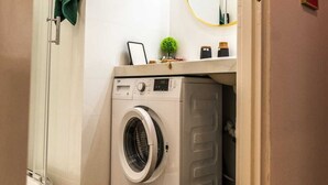 A compact laundry room with a washing machine, a small plant, and a mirror. - Górna Royal Red Apartment (Lublin)
