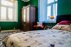 Une chambre à coucher comprenant un lit, une armoire, une fenêtre avec des rideaux et une table de chevet avec une lampe.