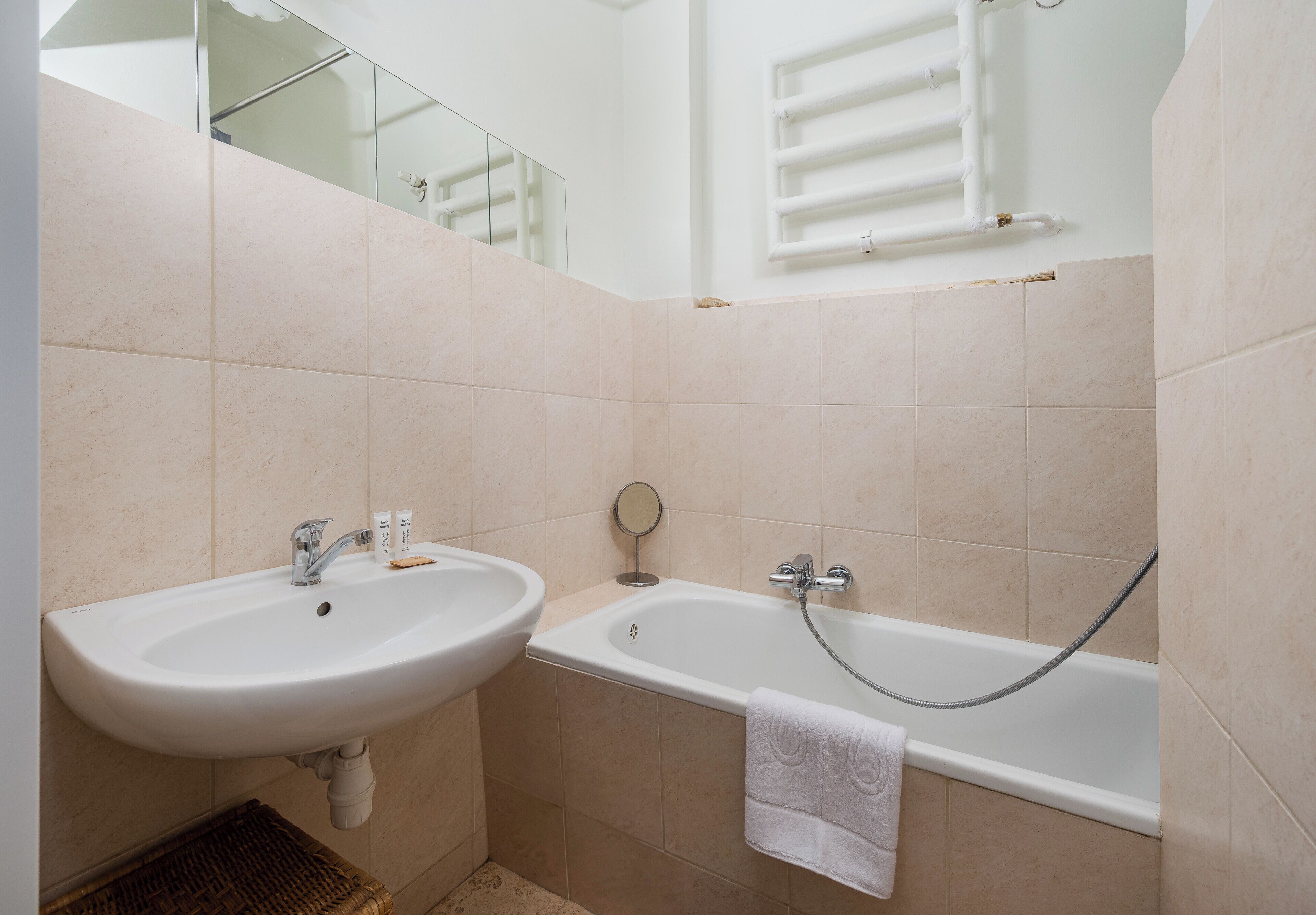 A bathroom with a sink, mirror, and bathtub.