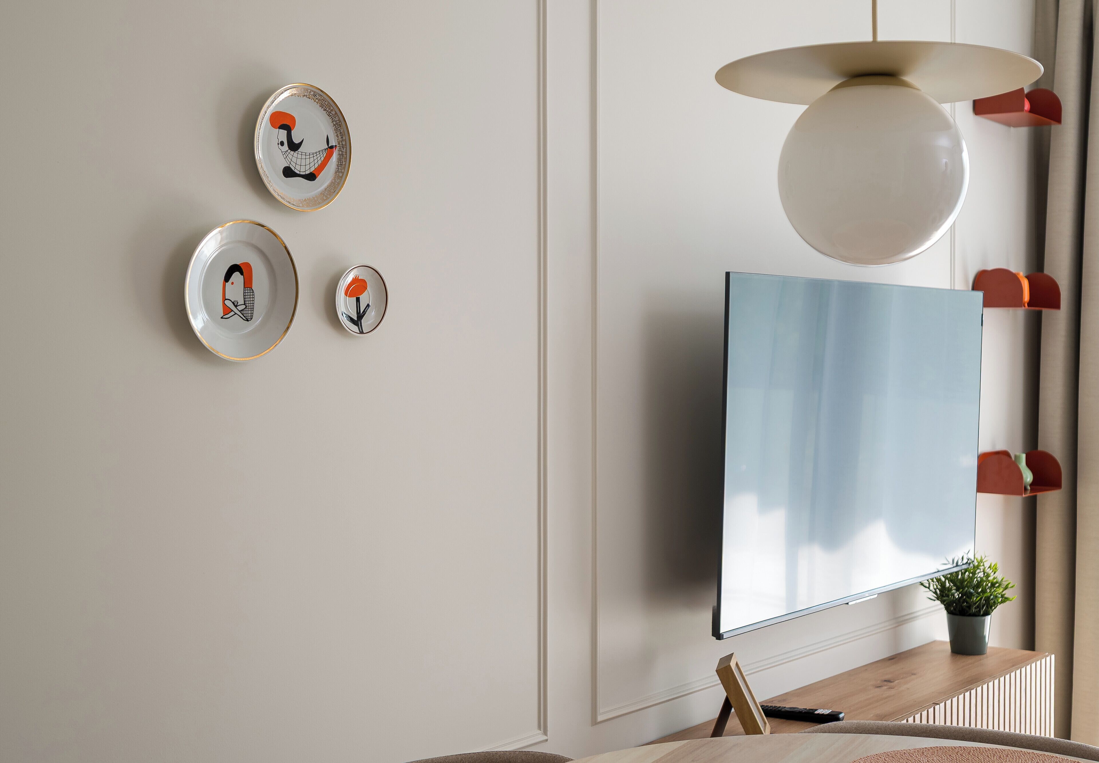 Un salon moderne avec un téléviseur à écran plat fixé au mur, une table basse en bois et une plante en pot.