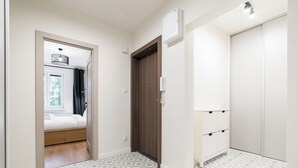 A hotel room with a bed, a wardrobe, a telephone, and a window with curtains. - Osiedle Sobieskiego Comfort Apartment (Poznań)