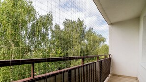 A balcony with a metal railing overlooking a dense green forest. - Osiedle Sobieskiego Comfort Apartment (Poznań)
