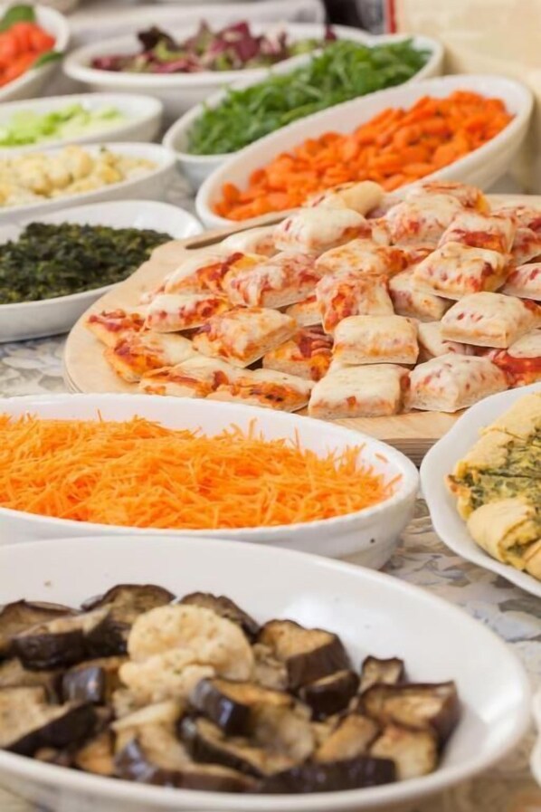A buffet with various dishes including sliced vegetables, cheese, and other food items. - Hotel Luca (Cesenatico)