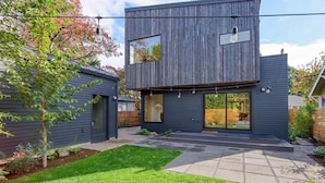 A modern two-story house with a dark exterior, a visible garage, and a well-maintained lawn.