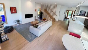 Een moderne woonkamer met een witte bank, een salontafel en een trap.