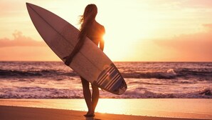 A person carrying a surfboard on a beach at sunset. - Best room with WiFi in taghazout (agadir)