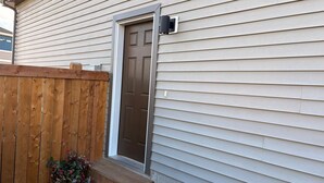 A house with a wooden fence, a front door, and a small step leading to the door.