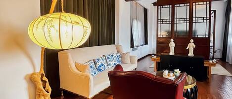 A room with a sofa, a red chair, a table with a lamp, and a decorative piece.