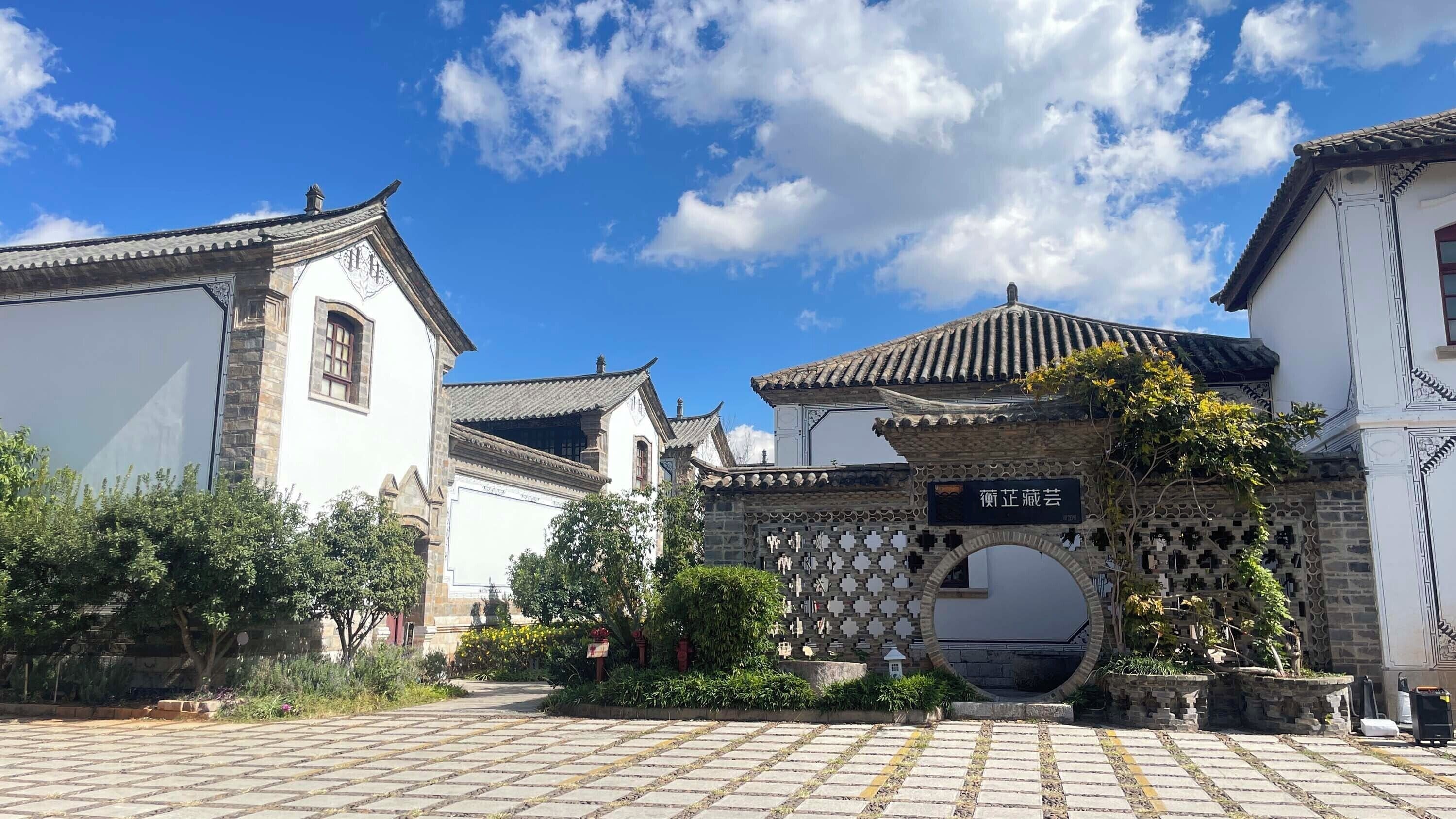 A traditional Chinese architectural entrance with a tiled roof and a stone archway.