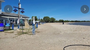 A beach area with a building, a lighthouse, and a parking area. - Top floor Lakeview Hotel 1 Bd available July 31 - Aug 7 Icelandic festival week (Gimli)