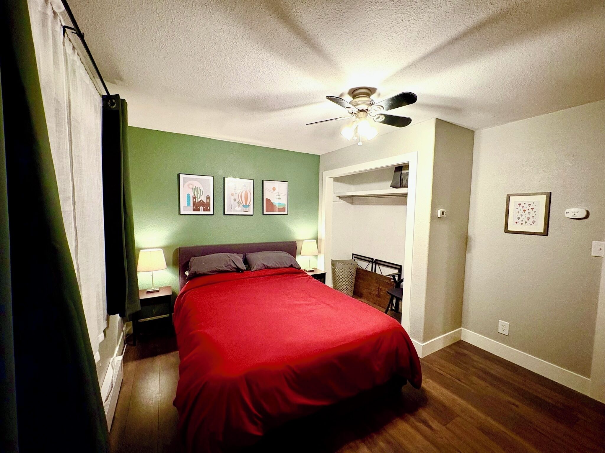 Une chambre à coucher avec un lit, un ventilateur de plafond et trois tableaux encadrés accrochés au mur.