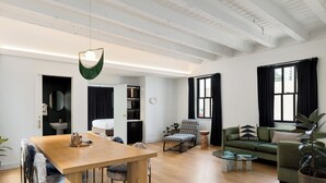 Un salón espacioso con una mesa de comedor de madera, un sofá verde, un sillón mecedora y una mesa baja.