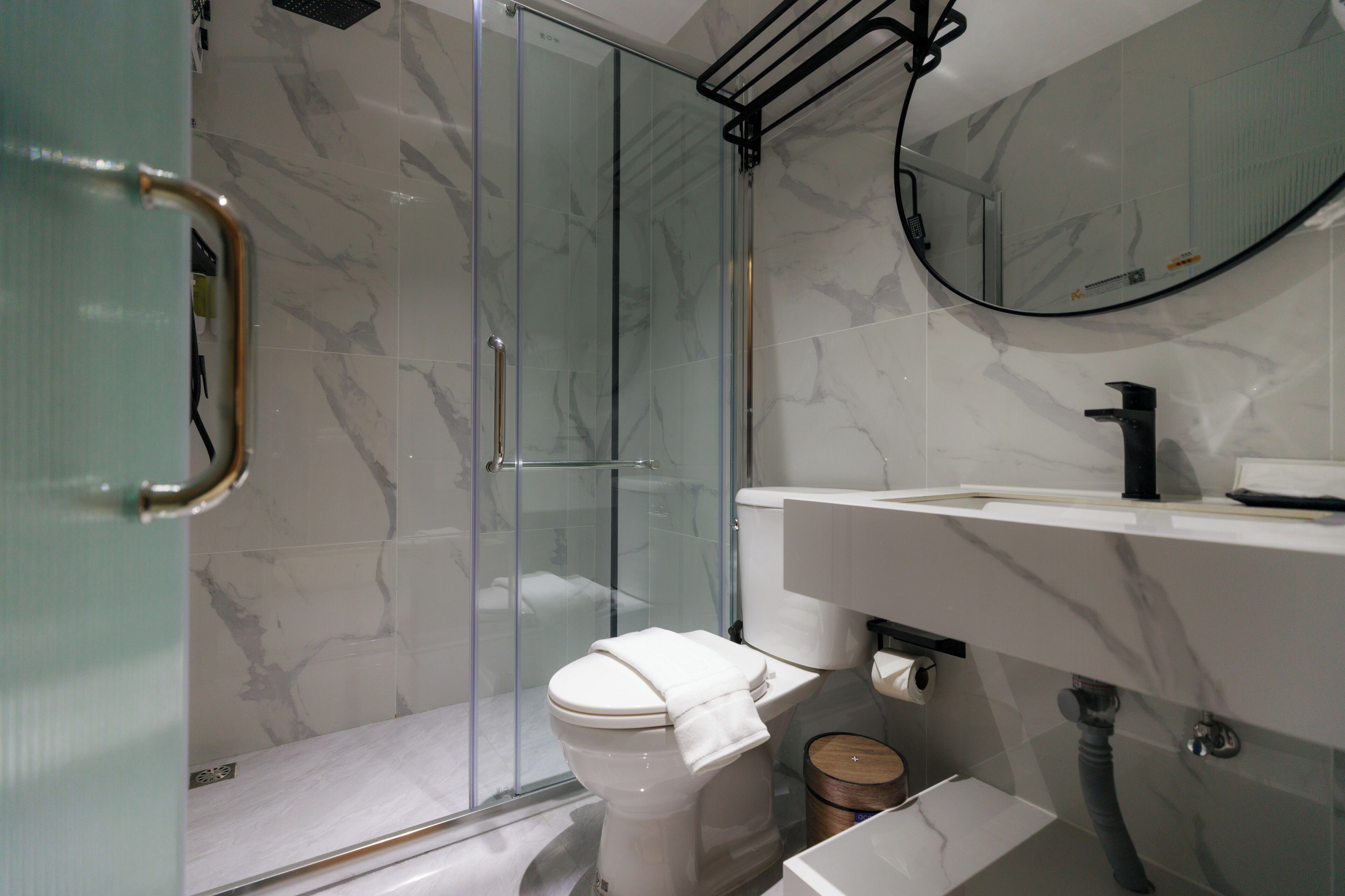 Ein modernes Badezimmer mit einer Duschkabine aus Glas, einer weißen Toilette und einer Wand mit Marmorplatten.