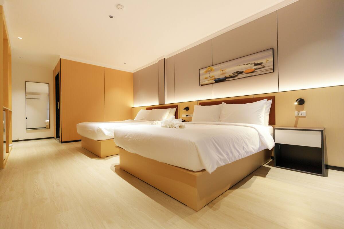 A modern hotel room with a large bed, a bedside table, and a wall-mounted artwork.