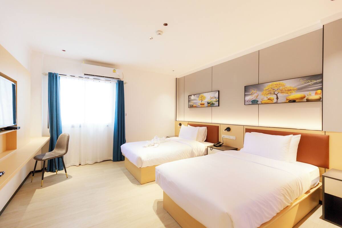 A hotel room with two beds, a desk, and a chair.