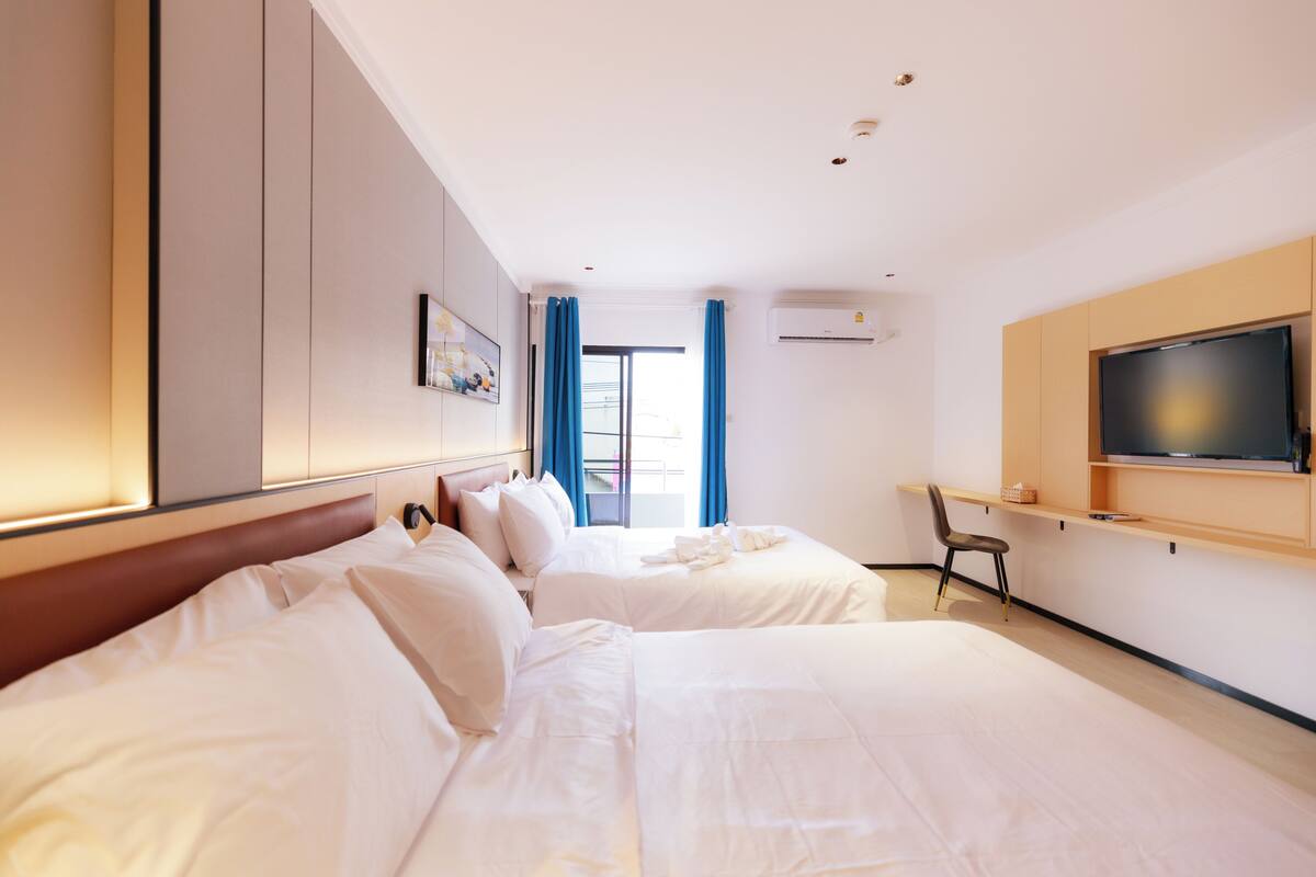 A hotel room with two beds, a TV, and a desk.