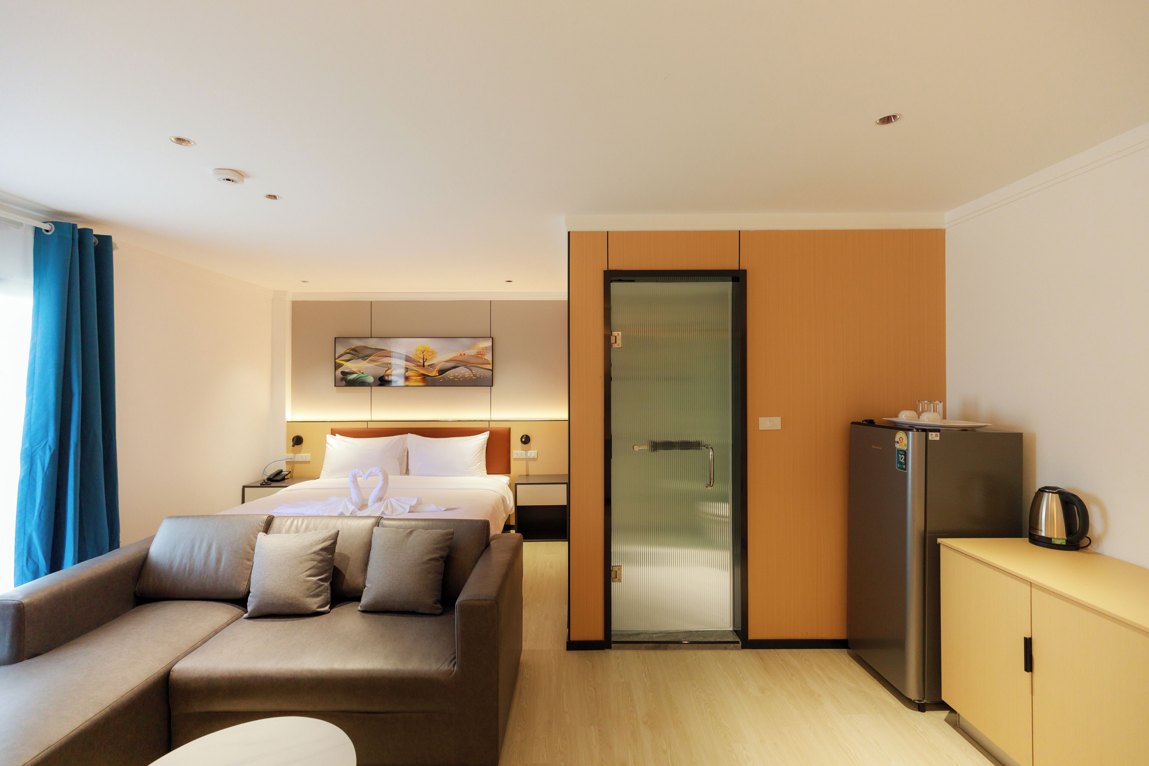 Une chambre d’hôtel équipée d’un lit, d’un canapé, d’un réfrigérateur et d’une porte vitrée donnant sur un balcon.