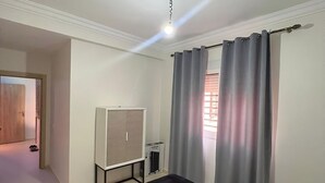 Un dormitorio con cama, armario, radiador y puerta que da a otra habitación.
