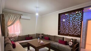 Una sala de estar con un conjunto de sofá, una mesa de centro y un panel decorativo en la pared.