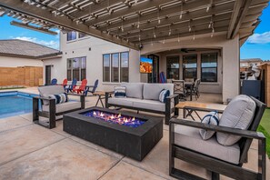 Une terrasse extérieure avec un foyer, des sièges et une piscine.