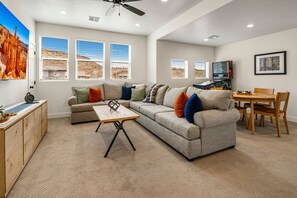 A living room with a sectional sofa, a coffee table, a dining table with chairs, and a ceiling fan. - Paseos Retreat: 2 Luxury Homes w/ Pool, Hot Tubs, Game Rooms, & Resort Access (Washington)