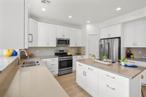 A modern kitchen with white cabinetry, stainless steel appliances, and a central island with seating.
