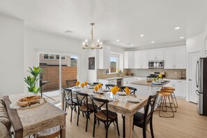 A modern kitchen with white cabinets, a central island, and a dining area with a wooden table and chairs.