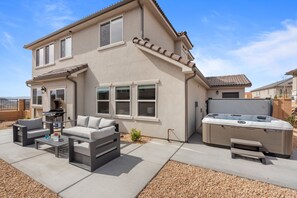 A two-story house with a patio area featuring outdoor furniture and a hot tub. - Paseos Retreat: 2 Luxury Homes w/ Pool, Hot Tubs, Game Rooms, & Resort Access (Washington)