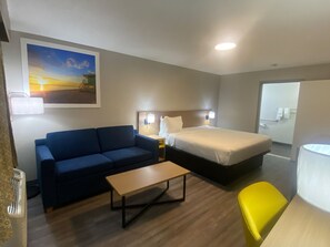 Una habitación de hotel con cama, sofá, una mesita y una silla.